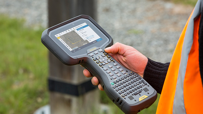 field working holding TSC510 near street pole