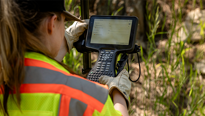 female surveyor holding TSC710 in marsh