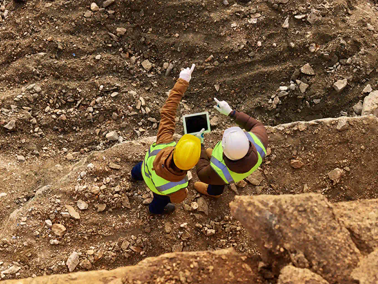 two land surveyors surveying dig site