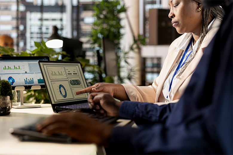 two consultants pointing a graph on a laptop screen 