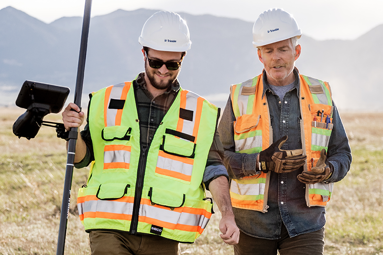two land surveyors walking in an open field