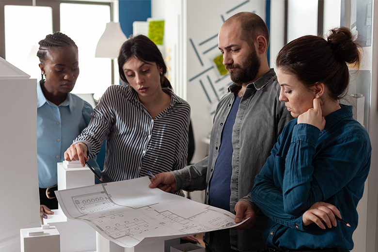 four engineers looking over printed construction plans